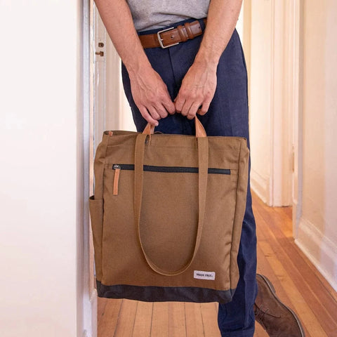 Man holds the tote pack from veg tanned leather straps