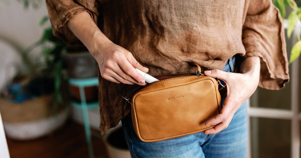 woman unzipping leather fanny pack around waste