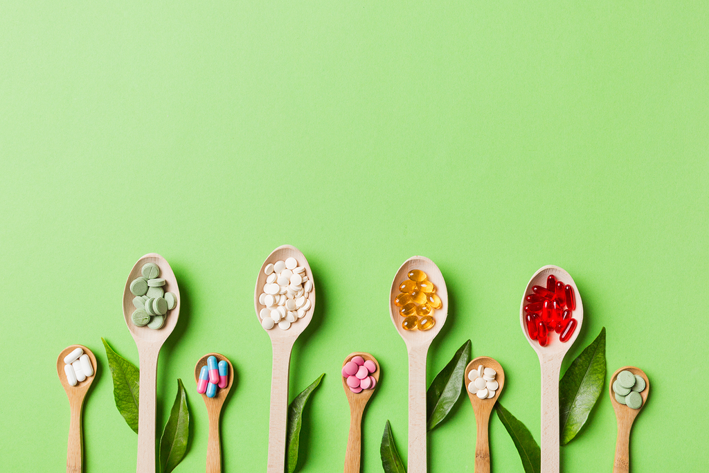 Medicines and vitamins in separate wooden spoons, which represents the meaning of "Food is medicine".