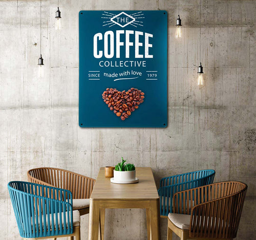 A cafe interior with table and chairs. A concrete wall has a metal wall art panel printed with the coffee shop's logo