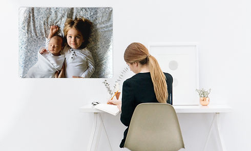 A woman working in a home office with a 'Create your own' magnetic board with a photo of a young child and baby on it