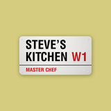 A personalised steel London street sign on a yellow background with Steve's Kitchen, master chef printed on it