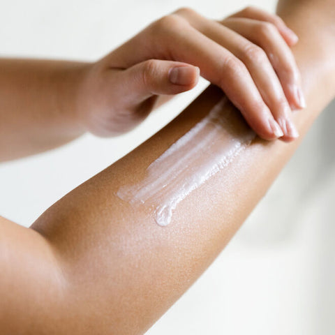 A person applying lotion to their arm