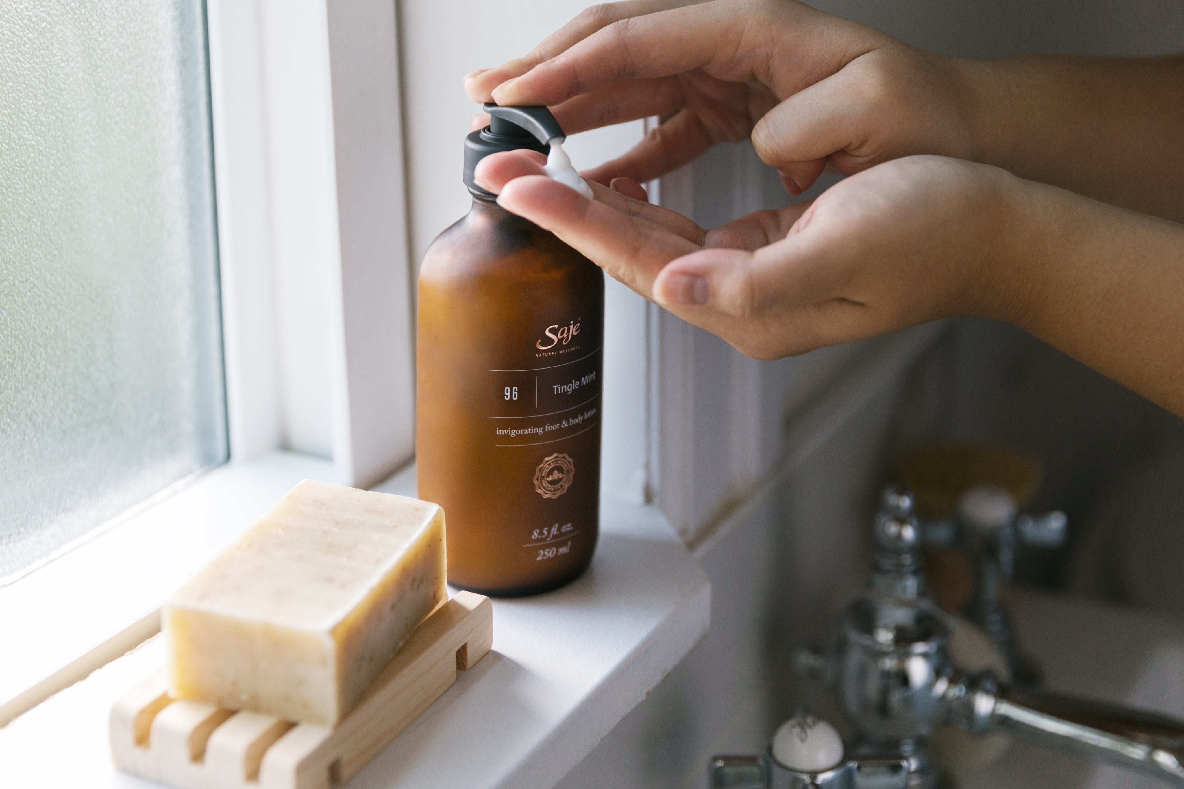 A hand dispensing tingle mint body lotion into their hand