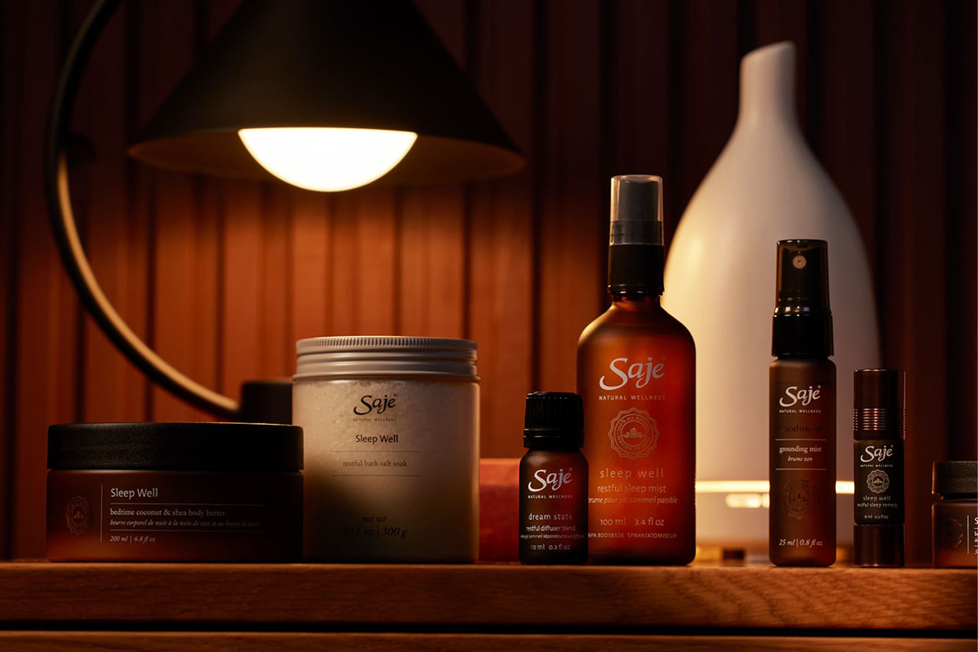 A collection of Saje sleep products on a wooden nightstand
