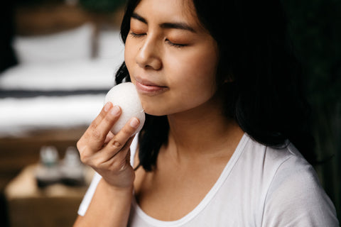 A woman using a facial sponge to exfoliate her skin