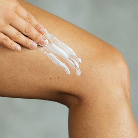 A person applying body butter to their thigh