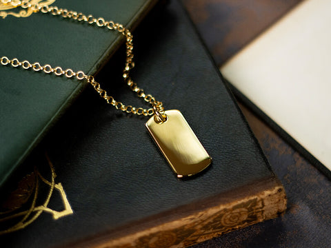 gold dog tag necklace for men photographed on leather book