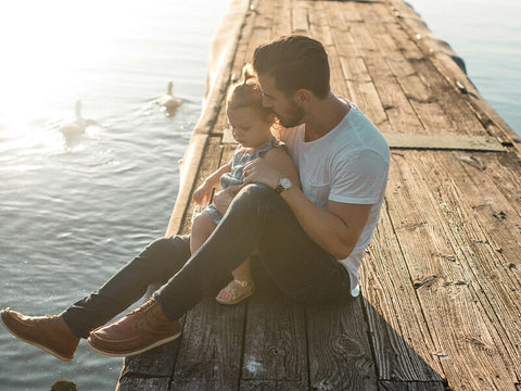 father sitting with daughter on wooden pier