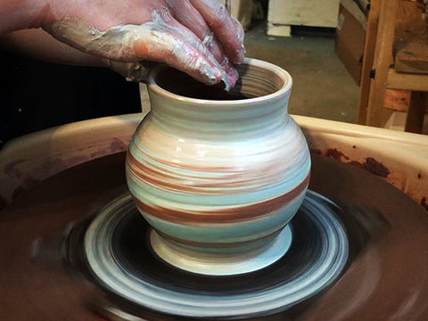 Using porcelain and red clay to form on potter's wheel.