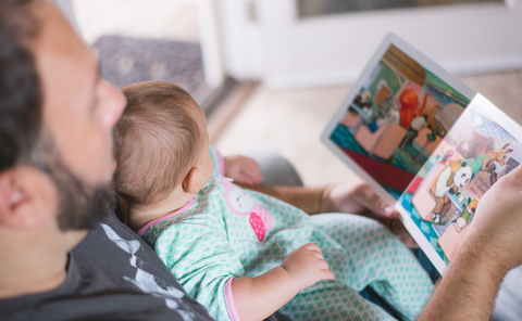 Man with a baby on his lap, reading a picture book.