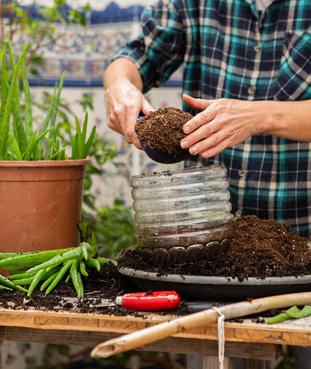 Man wearing blue plaid shirt gardening with his bare hands