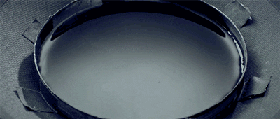 Animated GIF of a pan filled with water, showing symmetrical ripples emanating from the centre of the pan.