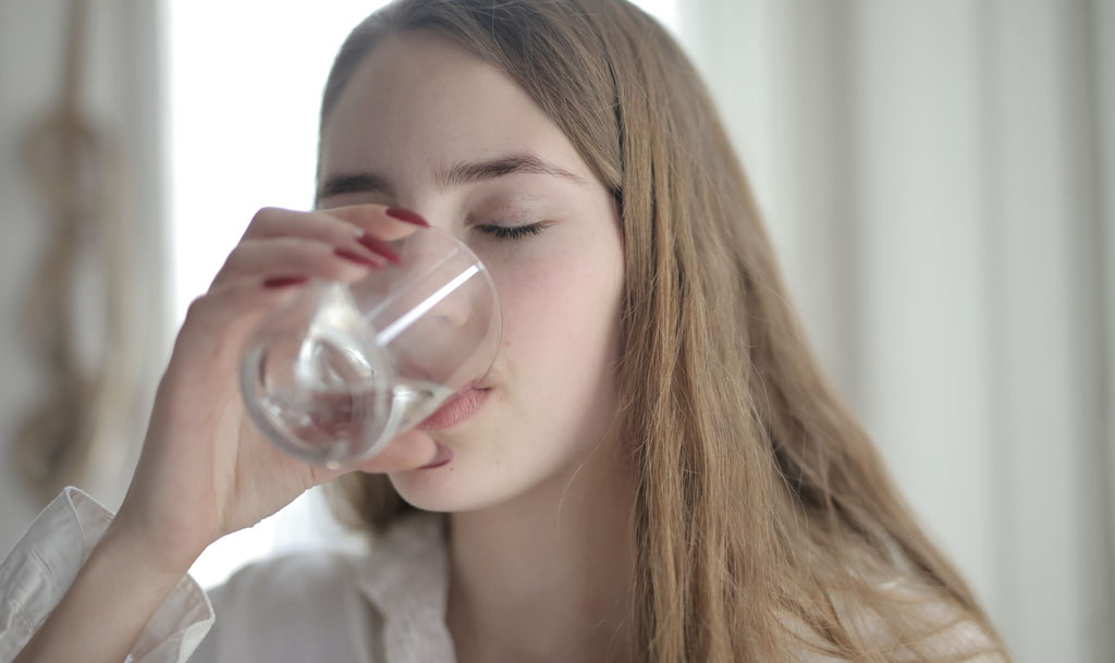 Eine Frau trinkt ein Glas Wasser.