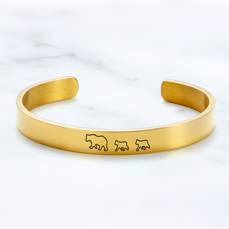 Mama Bear & Her Baby Bears Engraved Cuff Bracelet with gold plating on a marble background