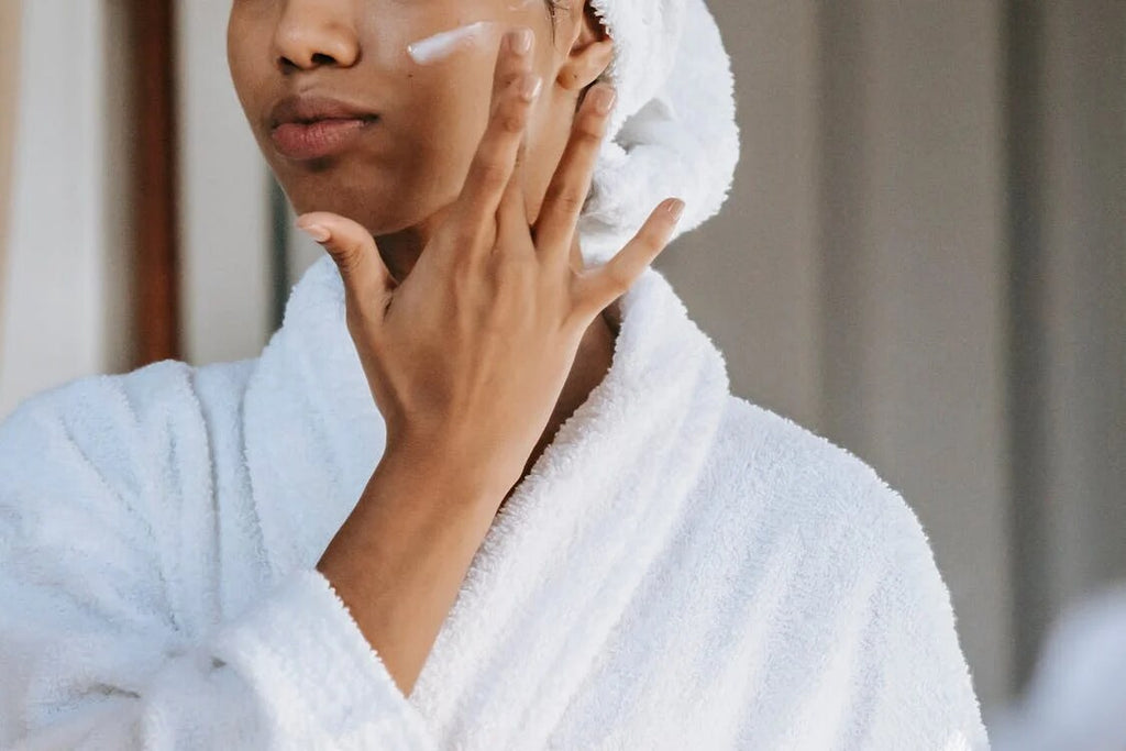 A woman wearing a white robe applying face cream