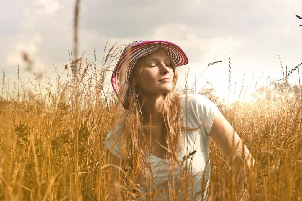 A woman standing in a wheat field on a sunny summer day