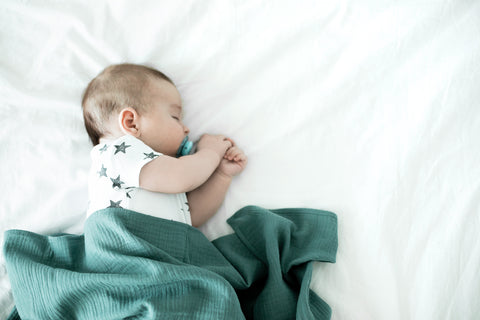 Bébé dormant sous un lange en gaze de coton