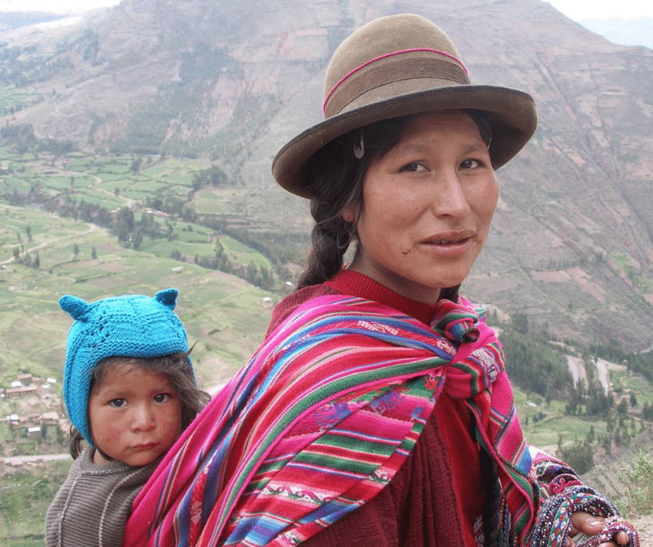 Quechua woman in traditional clothing wearing her baby in the Sacred Valley in Peru