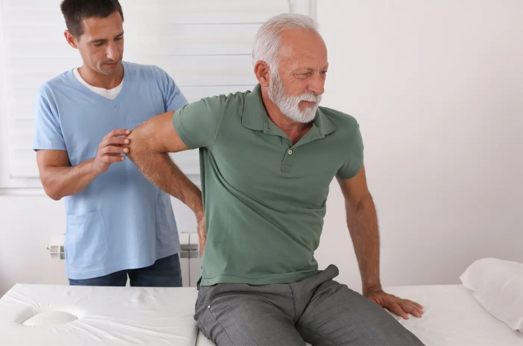 homme âgé qui se tient le bas du dos avec un médecin derrière lui