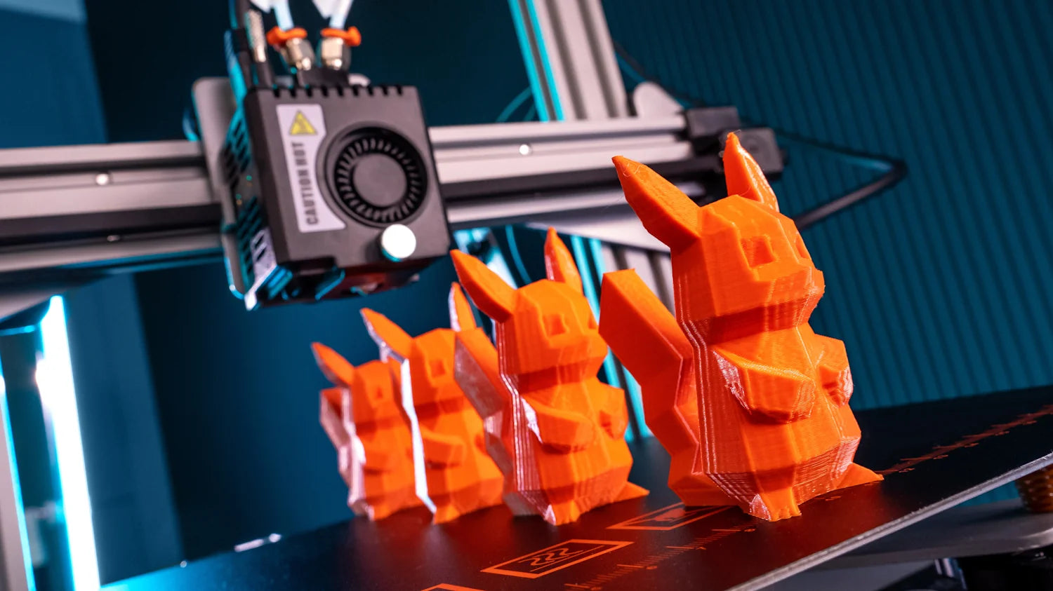 3D printer with multiple printed objects on the print bed using orange filament