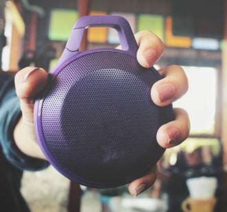 hand holding purple bluetooth speaker