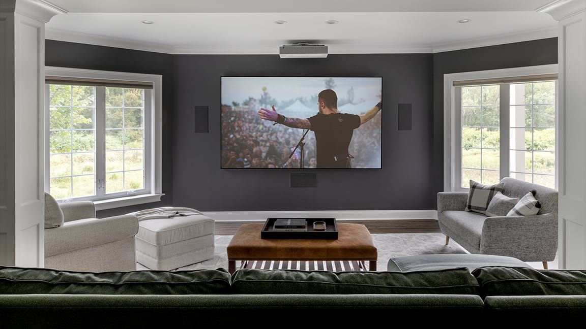 home theater with in-wall speakers, projector, and projector screen and open Lutron shades
