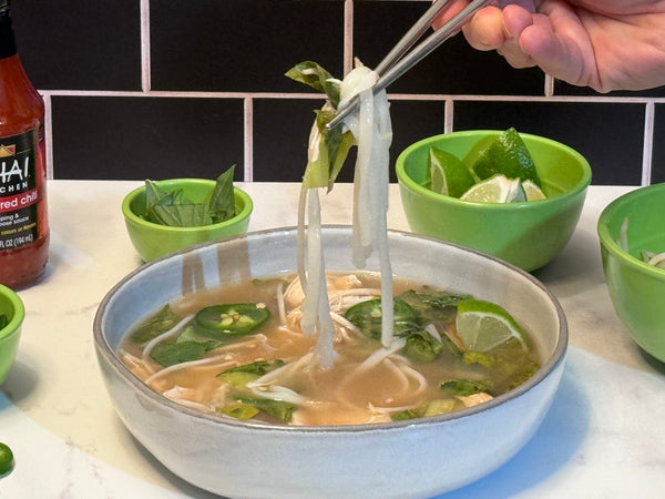 Chicken Pho with ingredients, pulling noodles out of the soup
