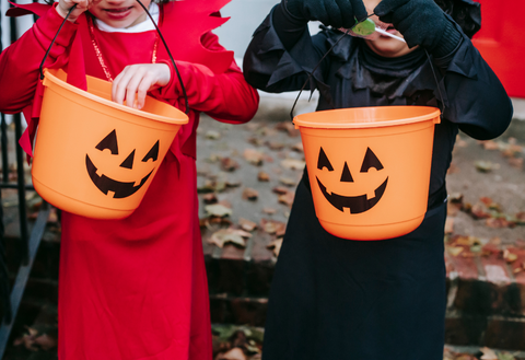 Kids holding halloween candy buckets