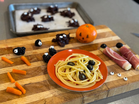 Spooky Lunch foods - buttered noodles with eye balls, mozzarella and prosciutto fingers, chocolate spiders and one-eyed blackberries
