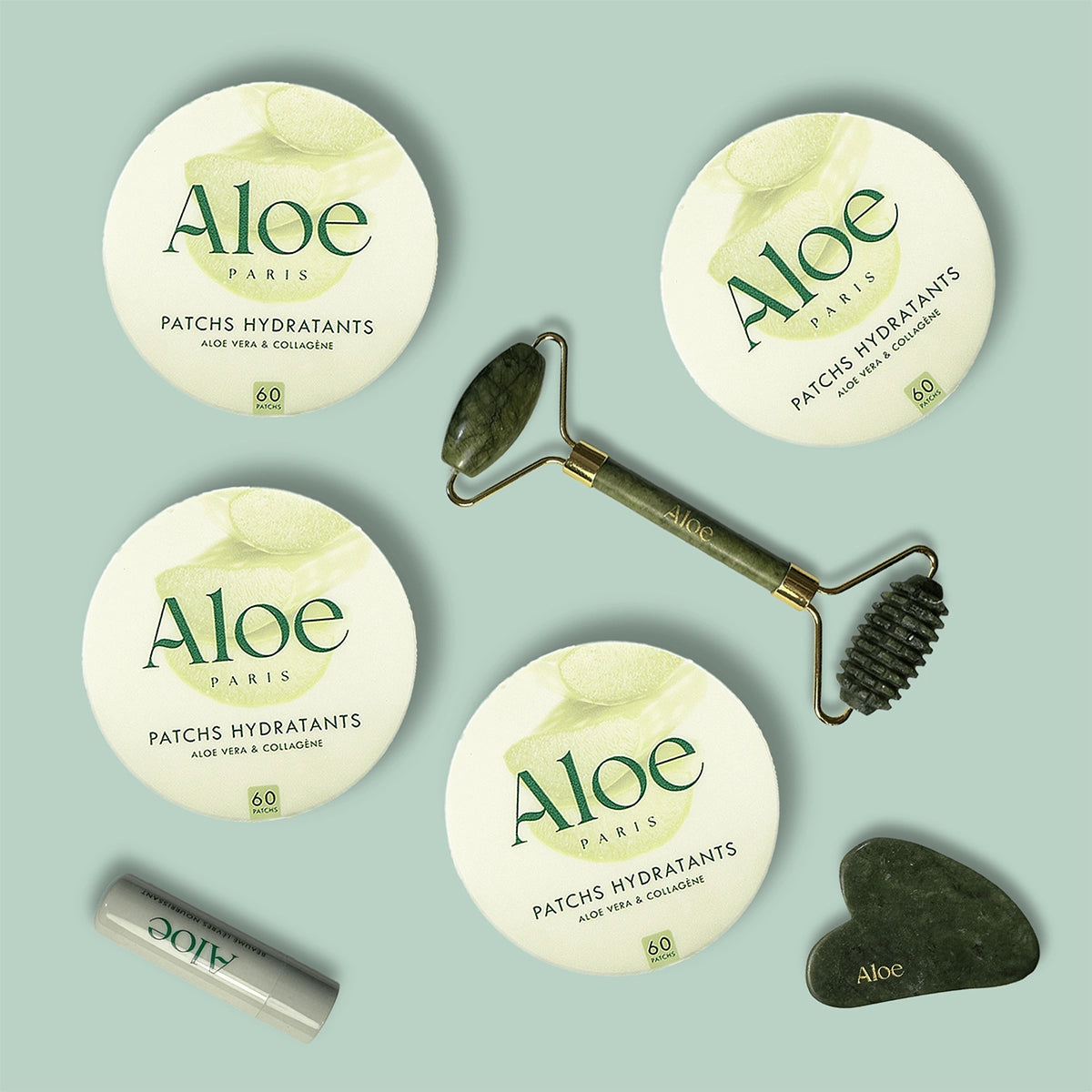 Aloe skincare products with jade roller and gua sha stone on a mint background.