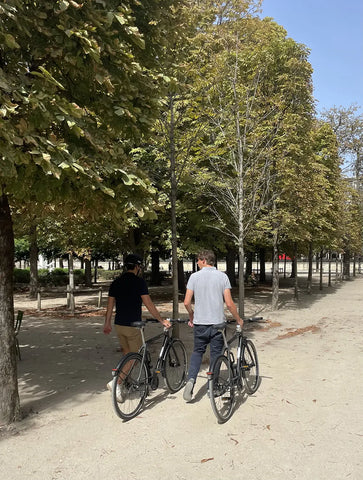 2 hommes qui se promènent dans un parc en tirant leurs deux vélos Bastille