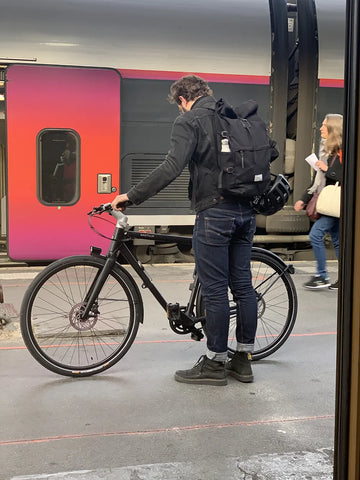 Homme sur un quai de RER en train de regarder son vélo Bastille déplié
