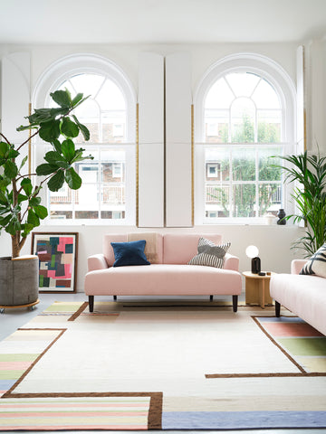 Pink Linen Sofa with White Walls and plants in front of two windows