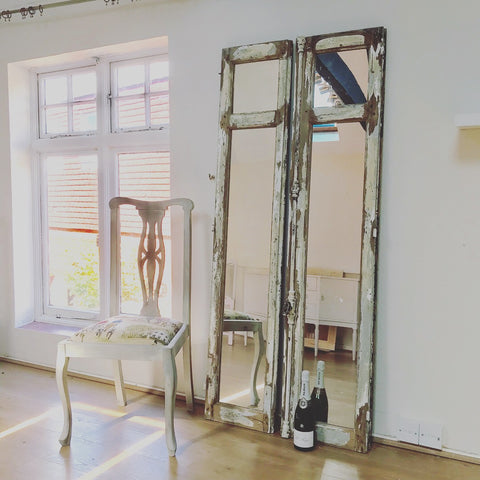 Mirrors and aged wood add texture to a white interior