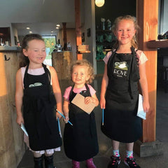 The owners' three children wearing black Rove Estate aprons and standing side by side.