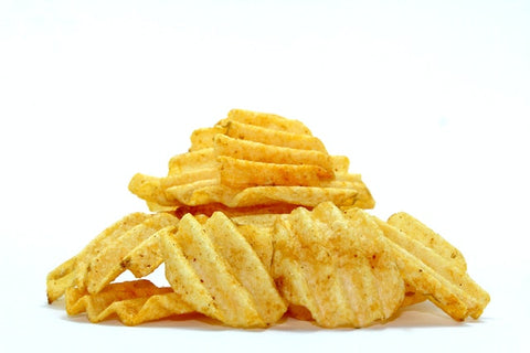 A shot of stacked ridged potato chips against a white background.