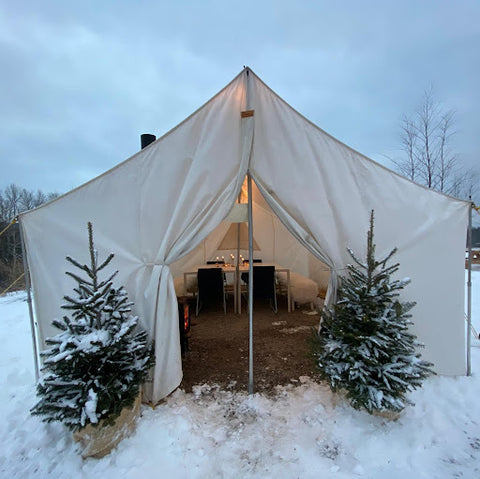 A photo of the Shepherd's Tent complete with two trees at the entrance and dining tables inside.