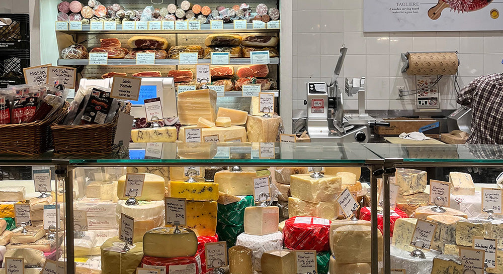 Cheese counter display with a large variety of cheeses.