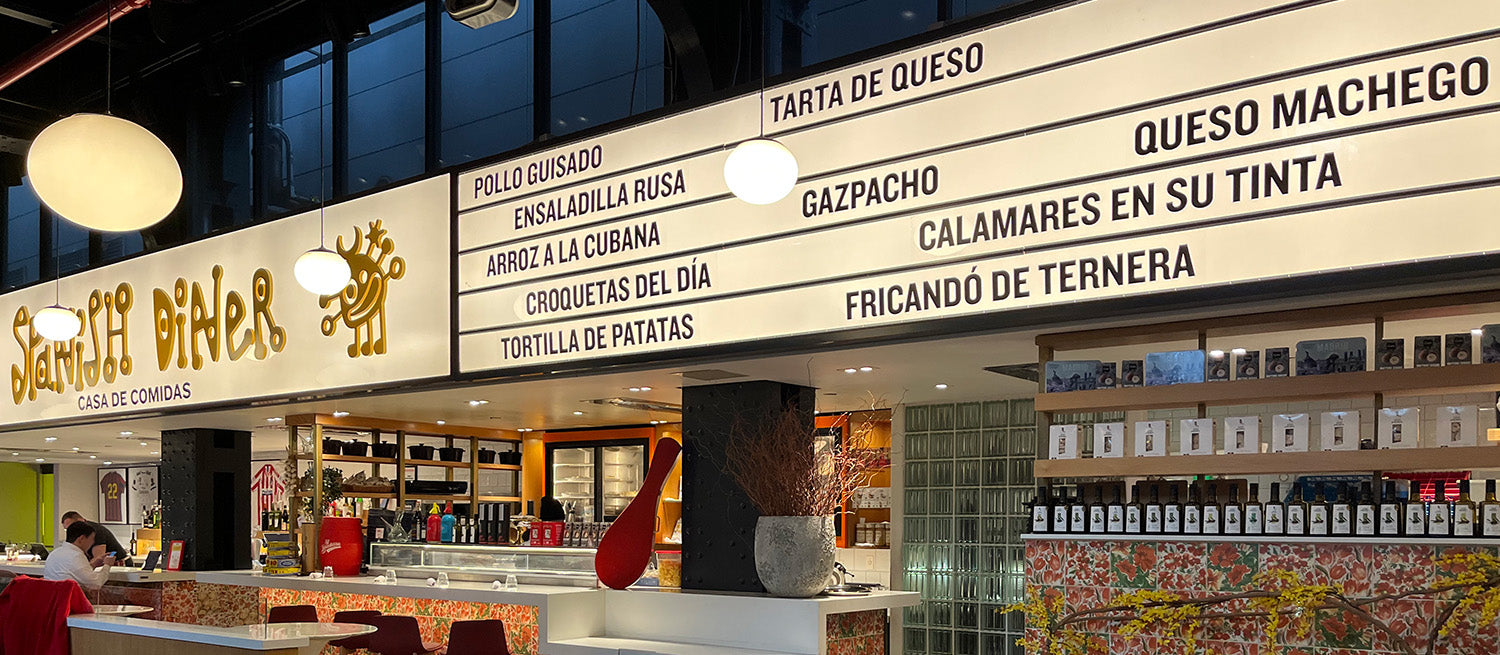A lit sign displaying the names of popular Spanish fast foods.