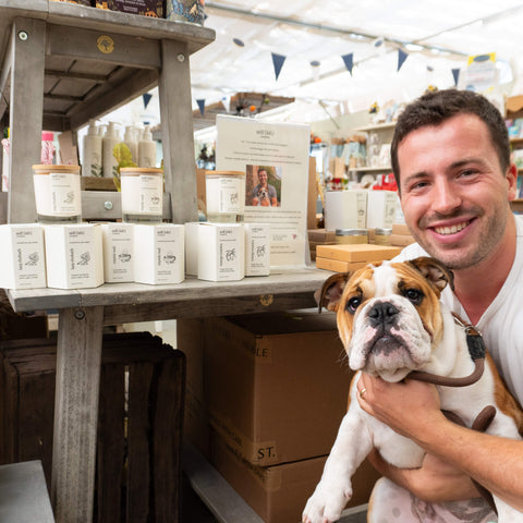 Become a Self (ish) Company Stockist or Retailer - Pictured is Charlie, the owner of Self (ish) Company with his dog, Monty, in front of an in store display stand featuring Self (ish) Company Scented Soy Wax Candles