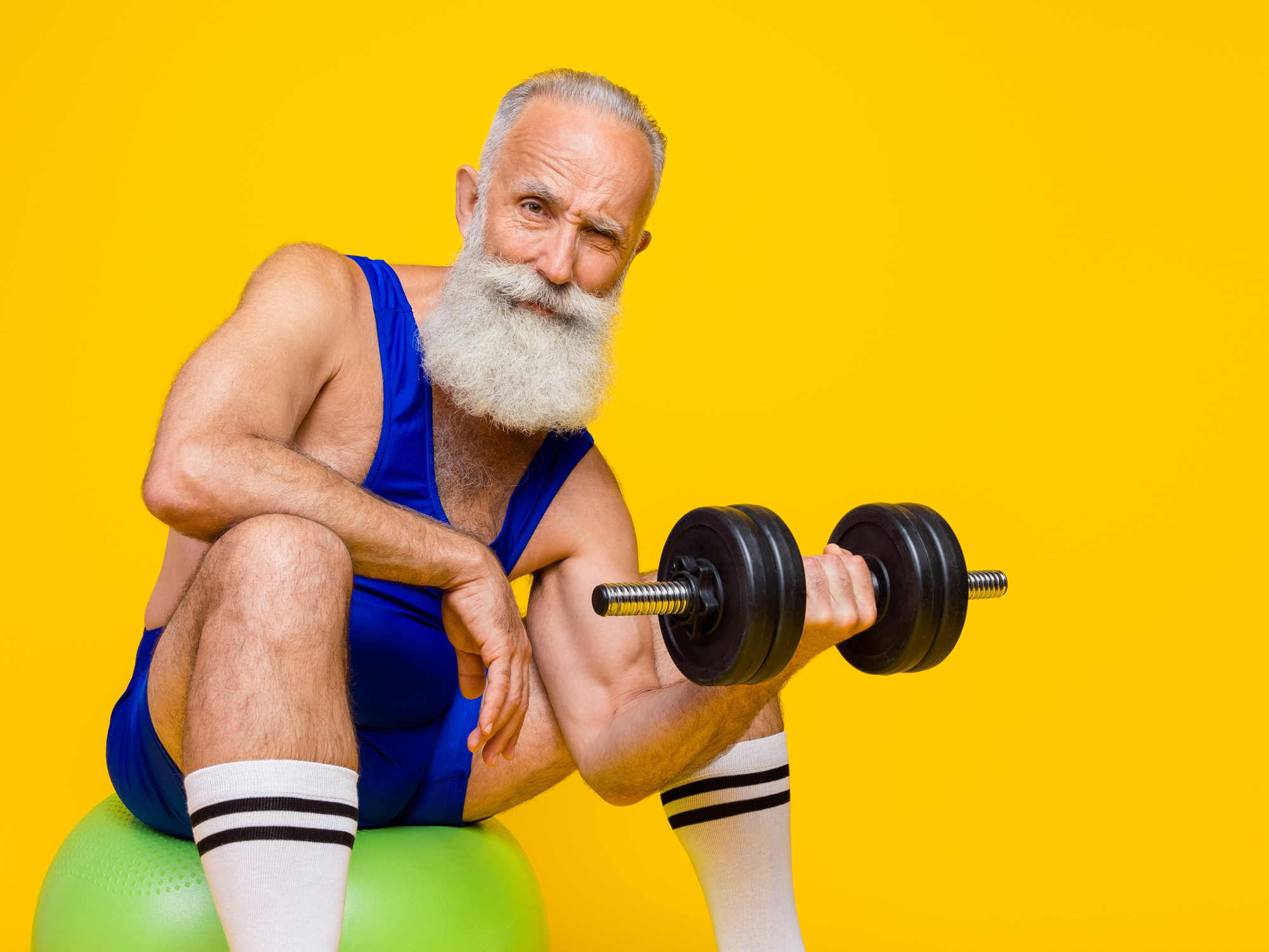 A fit, bearded man lifting a dumbbell in the gym