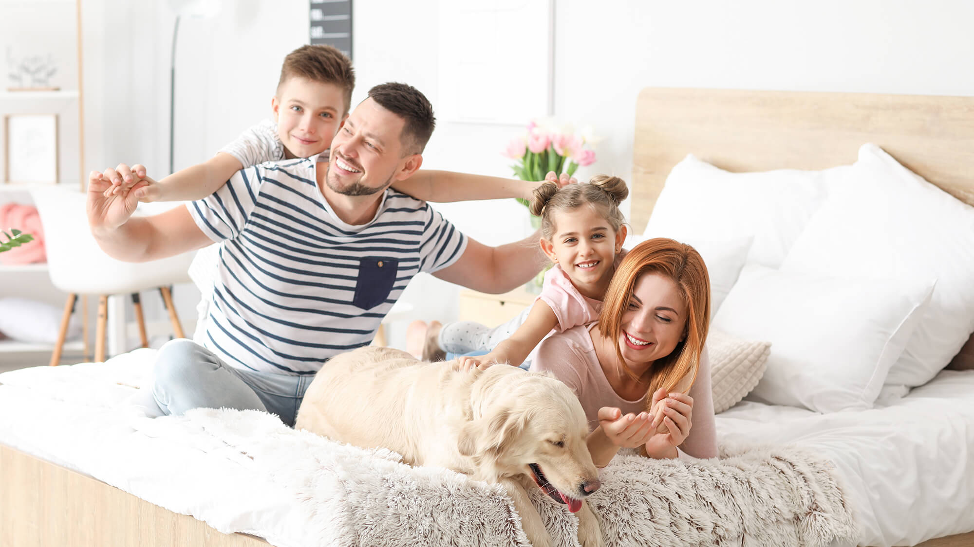 Familie mit Hund fröhlich im Bett