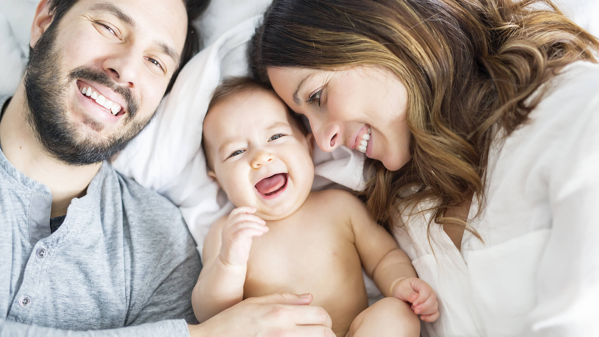 Familie liegt im Bett und lacht