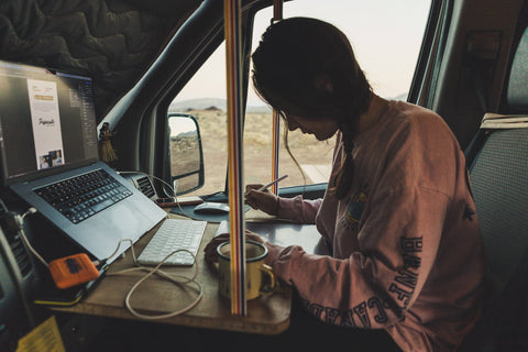 Woman sits at the desk in the camper and works