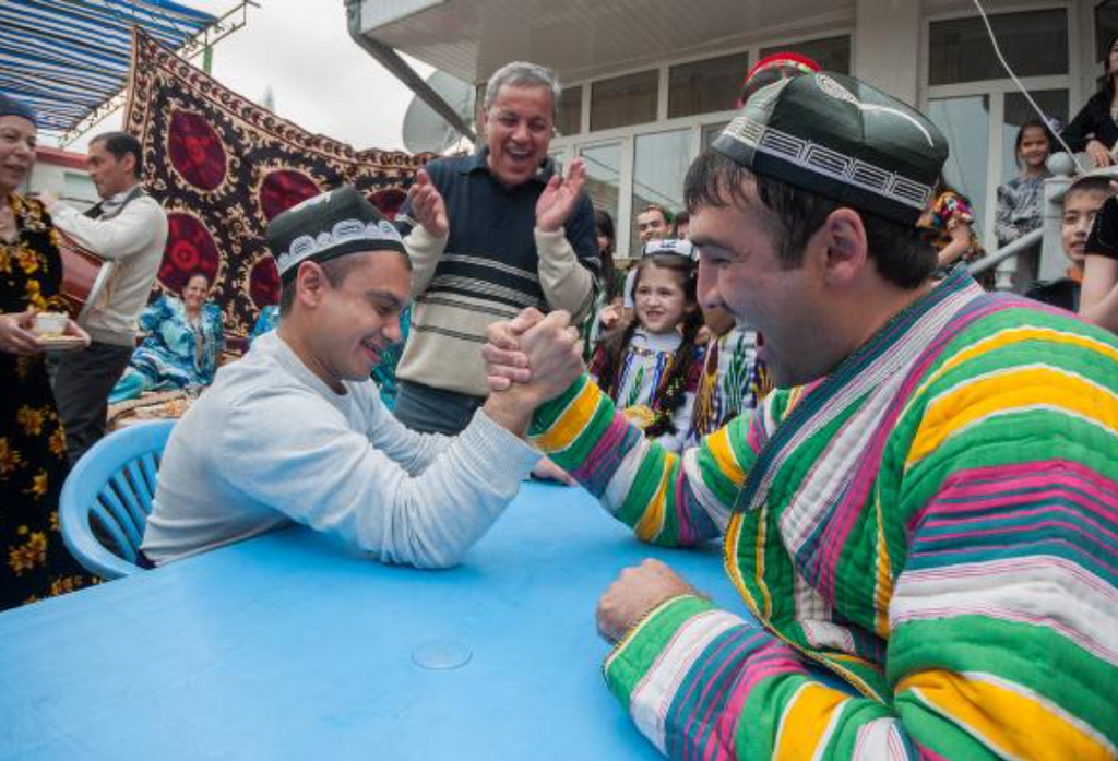 Two men in traditional dress arm wrestling at Navruz in Tajikistan 2016