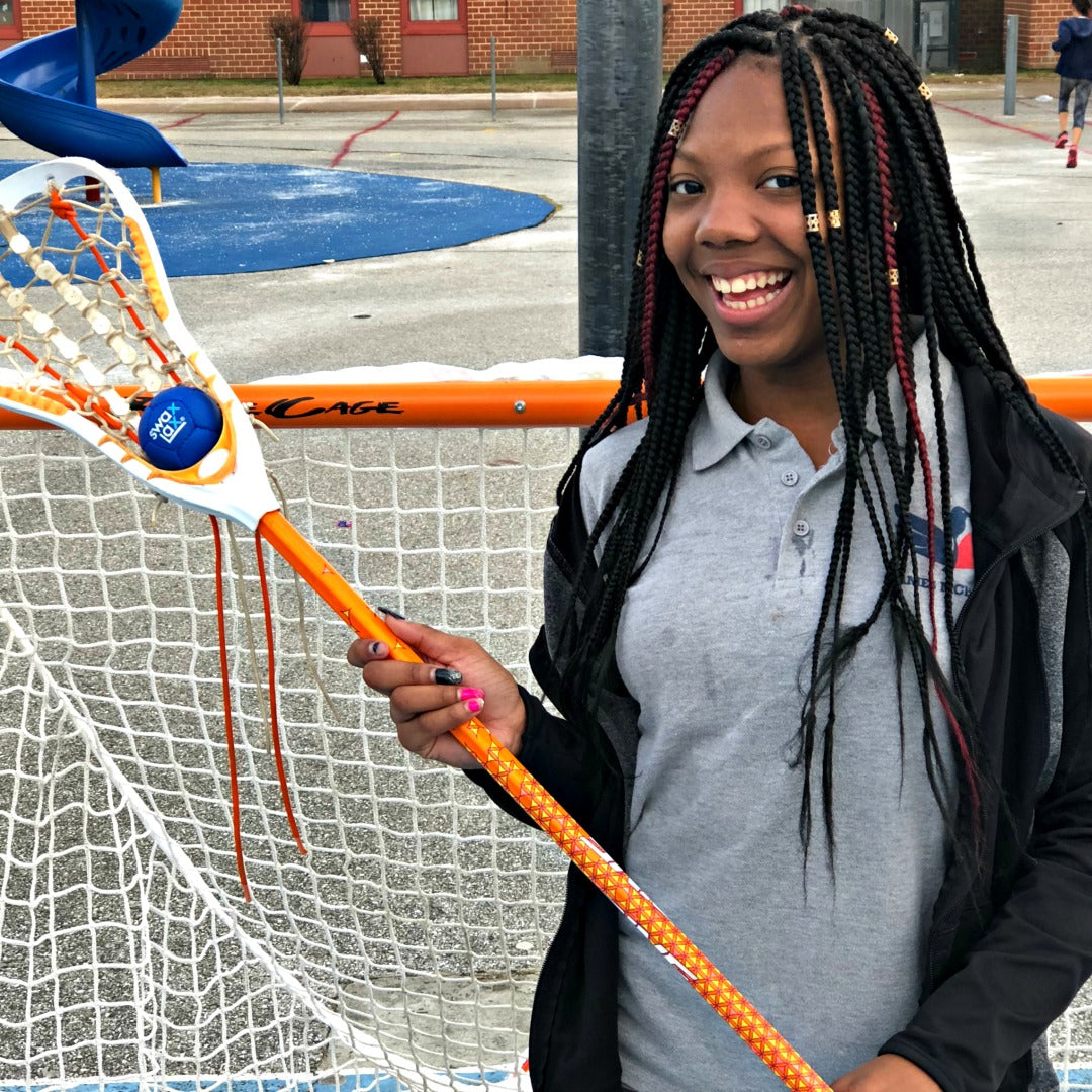 Harlem Lacrosse girl holding a blue Swax Lax ball in her lacrosse stick