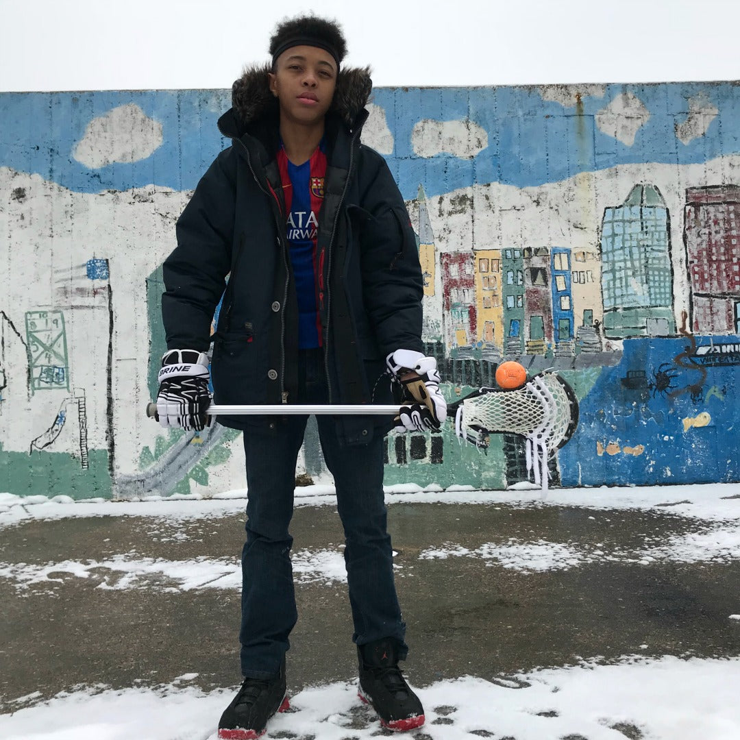 Harlem Lacrosse boy balancing a Swax Lax ball on his lacrosse stick