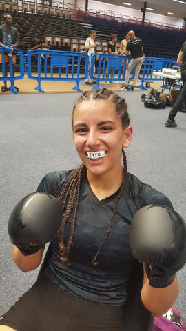 Femme qui porte une tenue de MMA et qui sourit avec un protège-dent Enyo
