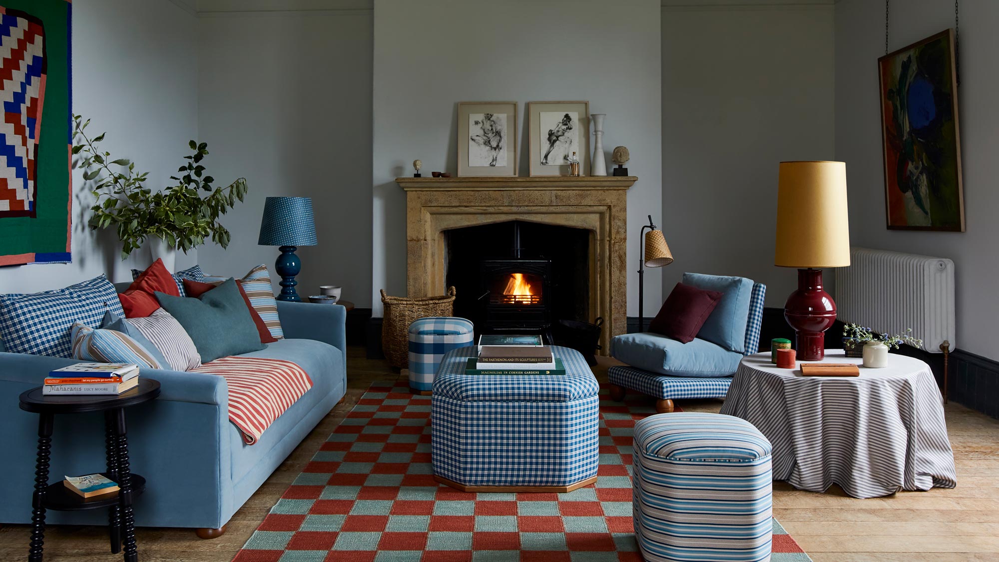 A living room with a blue sofa armchair and ottoman in front of the fireplace